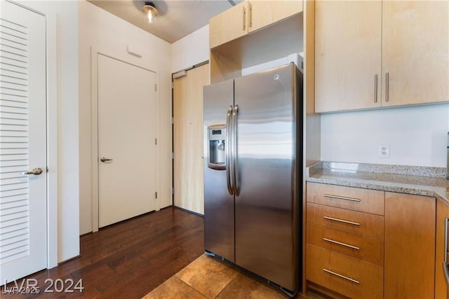 kitchen with light stone countertops and stainless steel refrigerator with ice dispenser