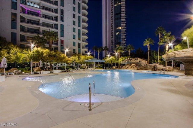 pool at twilight featuring a patio area