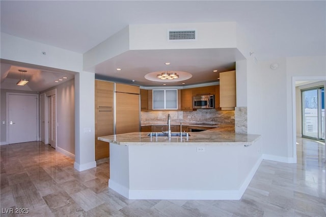 kitchen featuring light stone countertops, sink, kitchen peninsula, black electric cooktop, and paneled built in fridge