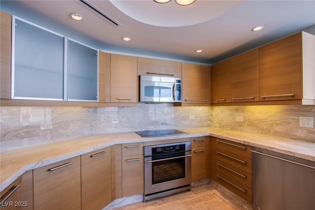 kitchen with backsplash, light stone countertops, and stainless steel appliances