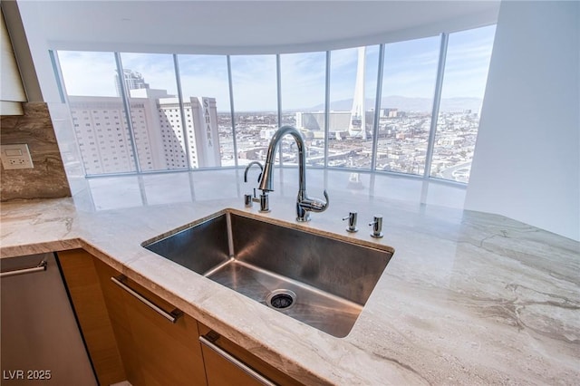 kitchen featuring decorative backsplash, light stone counters, and sink