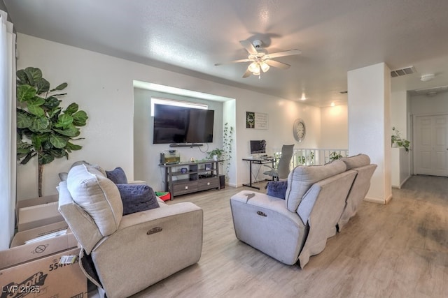 living room with ceiling fan, a textured ceiling, and light wood-type flooring