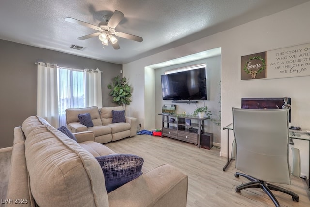 living room featuring ceiling fan, a textured ceiling, and light wood-type flooring