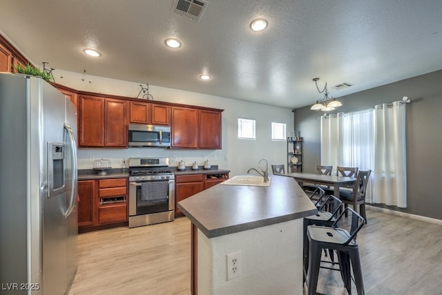 kitchen featuring appliances with stainless steel finishes, light wood-type flooring, sink, decorative light fixtures, and a chandelier