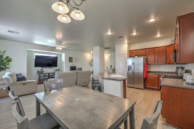 dining area featuring sink, ceiling fan with notable chandelier, and light hardwood / wood-style flooring