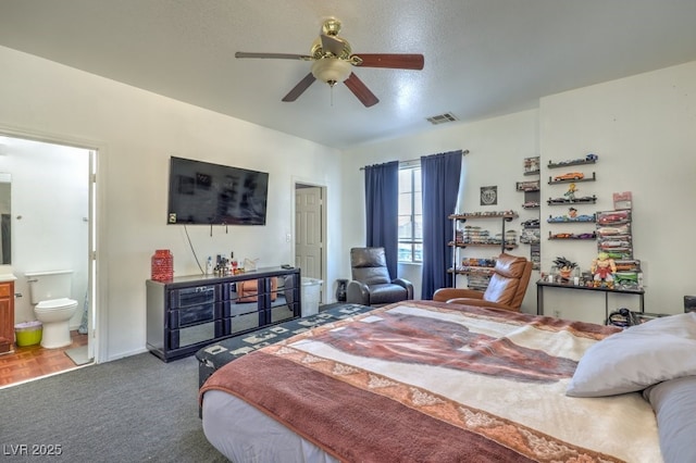 bedroom with ceiling fan, carpet floors, ensuite bathroom, and a textured ceiling