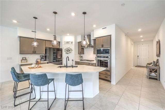 kitchen with a large island, sink, wall chimney range hood, tasteful backsplash, and appliances with stainless steel finishes