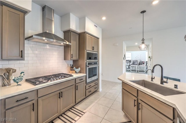 kitchen featuring tasteful backsplash, stainless steel appliances, sink, wall chimney range hood, and hanging light fixtures