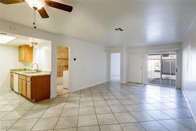 interior space with white dishwasher, sink, ceiling fan, light tile patterned floors, and washer / clothes dryer