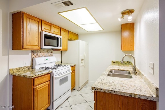 kitchen featuring white appliances, backsplash, sink, light tile patterned floors, and light stone counters