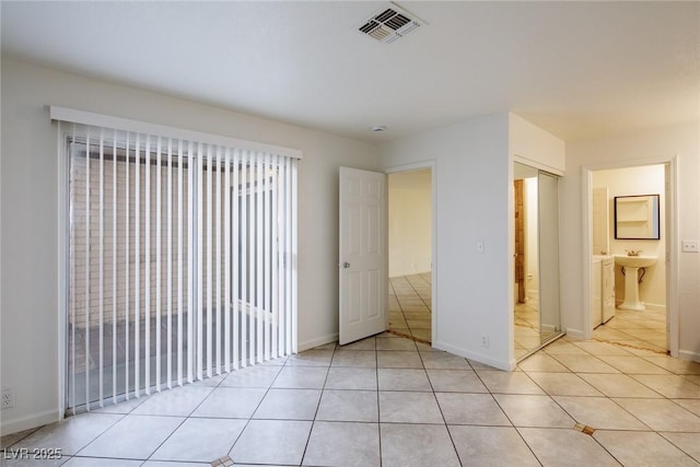 unfurnished bedroom with light tile patterned flooring, sink, and ensuite bath