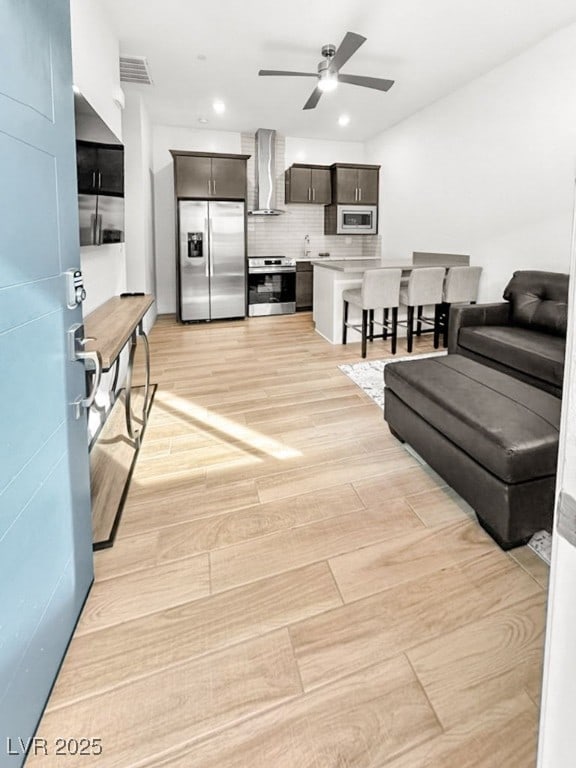 living room with ceiling fan and light wood-type flooring