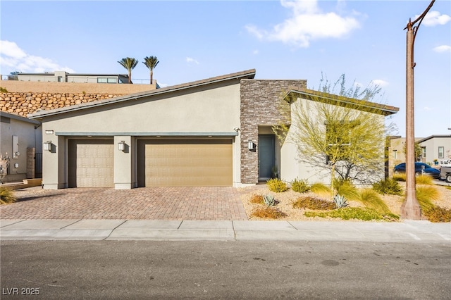 mid-century home with stucco siding, stone siding, decorative driveway, and an attached garage