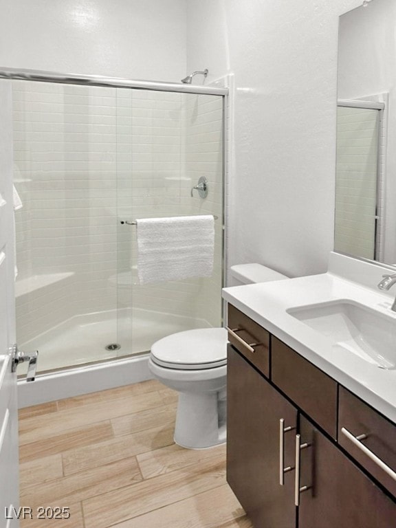 bathroom with vanity, hardwood / wood-style flooring, toilet, and an enclosed shower