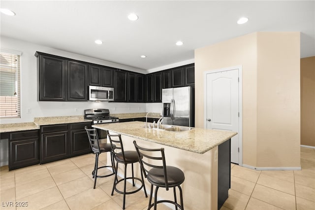 kitchen featuring a breakfast bar, a center island with sink, light tile patterned flooring, and appliances with stainless steel finishes