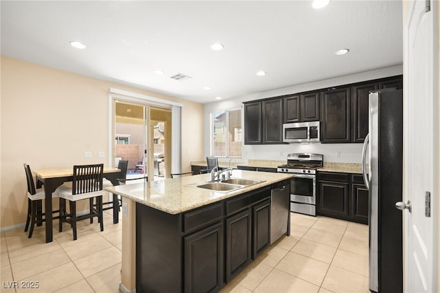 kitchen featuring light tile patterned floors, an island with sink, stainless steel appliances, and sink