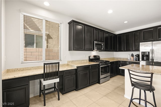 kitchen featuring a kitchen bar, light stone countertops, and stainless steel appliances