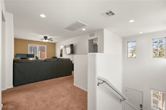 hallway with recessed lighting, visible vents, an upstairs landing, and light colored carpet