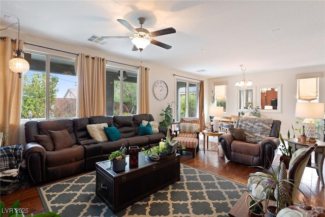 living room with dark hardwood / wood-style flooring, a healthy amount of sunlight, and ceiling fan with notable chandelier