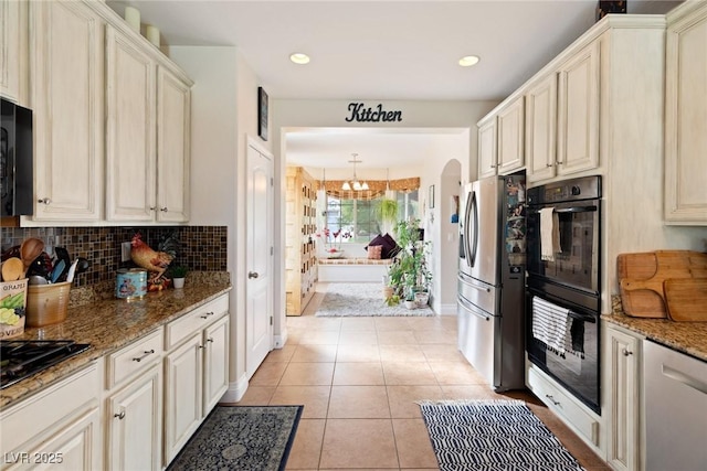 kitchen with stone counters, light tile patterned floors, cream cabinets, and black appliances