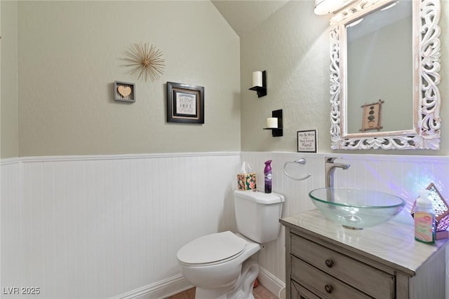 bathroom featuring vanity, toilet, and lofted ceiling