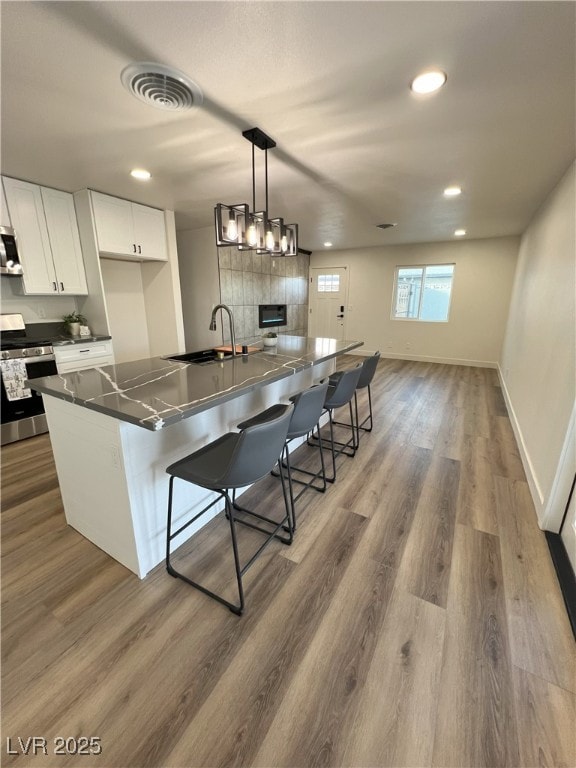 kitchen with a center island, sink, stainless steel appliances, a kitchen bar, and white cabinets