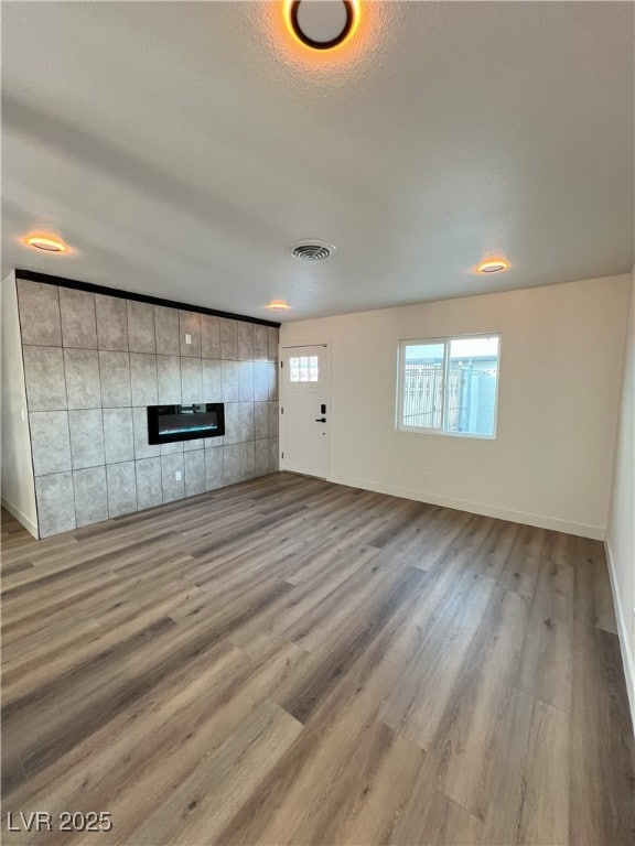 unfurnished living room with a textured ceiling, wood-type flooring, and a fireplace