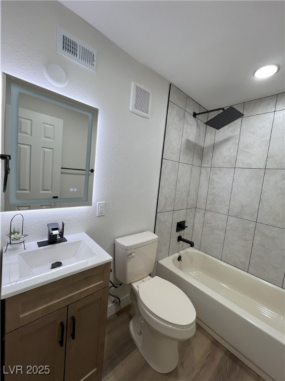 full bathroom with vanity, wood-type flooring, tiled shower / bath combo, and toilet