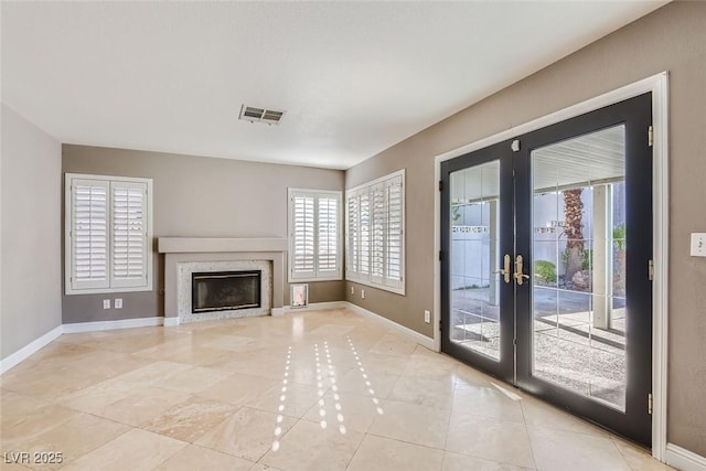 unfurnished living room with light tile patterned flooring, a fireplace, and french doors