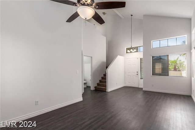 unfurnished living room featuring dark hardwood / wood-style flooring, high vaulted ceiling, and ceiling fan with notable chandelier