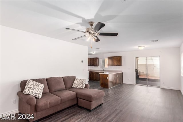 living room with dark hardwood / wood-style flooring, ceiling fan, and sink