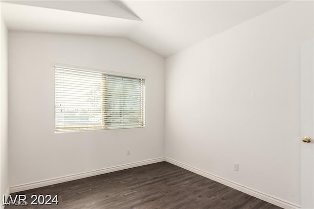 spare room featuring dark hardwood / wood-style flooring and lofted ceiling