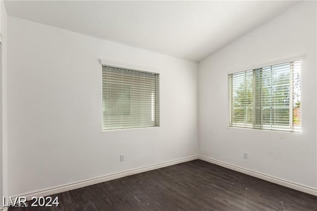 spare room with vaulted ceiling and dark wood-type flooring