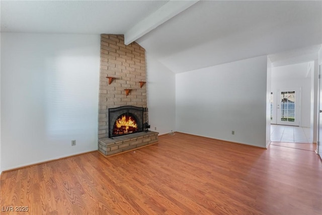 unfurnished living room with vaulted ceiling with beams, hardwood / wood-style floors, and a fireplace