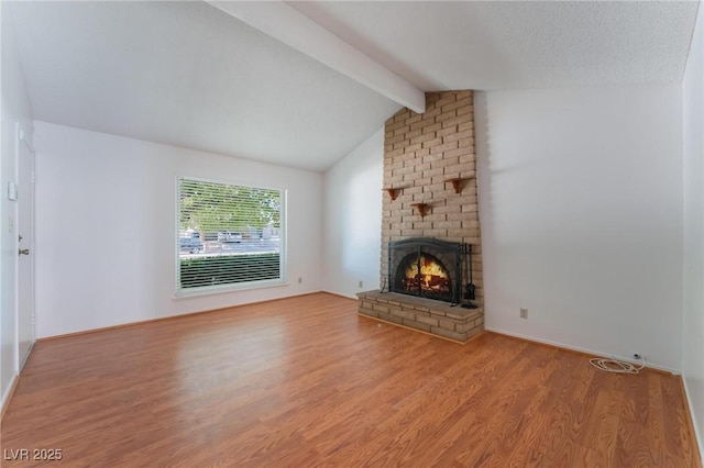 unfurnished living room featuring light wood-type flooring, a textured ceiling, lofted ceiling with beams, and a brick fireplace