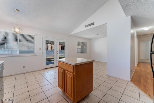 kitchen with pendant lighting, a kitchen island, lofted ceiling, and light tile patterned flooring