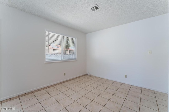 tiled empty room featuring a textured ceiling