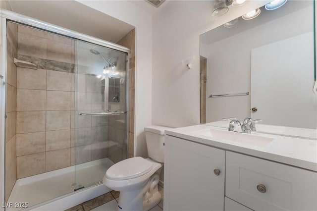 bathroom with tile patterned floors, vanity, a shower with shower door, and toilet