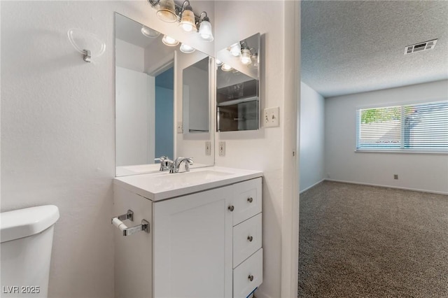 bathroom featuring a textured ceiling, vanity, and toilet