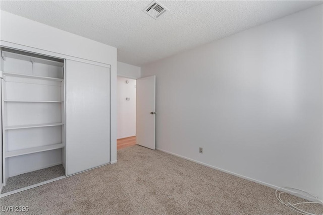 unfurnished bedroom with a closet, light colored carpet, and a textured ceiling