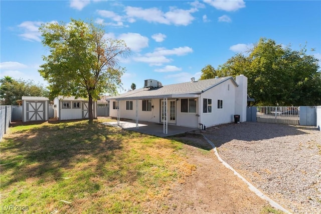 rear view of house featuring a patio area, a storage shed, and a lawn