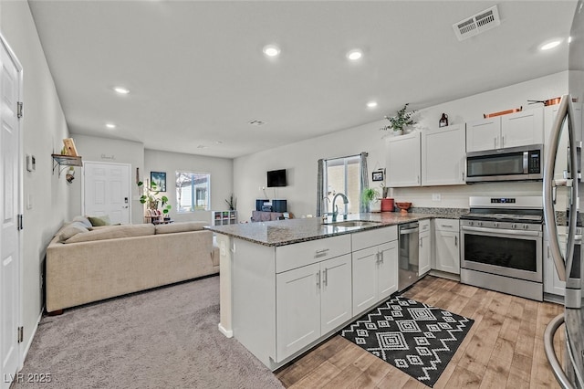 kitchen featuring appliances with stainless steel finishes, sink, white cabinets, light hardwood / wood-style floors, and kitchen peninsula