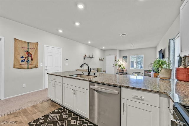 kitchen featuring sink, white cabinetry, stainless steel dishwasher, stone counters, and hardwood / wood-style floors