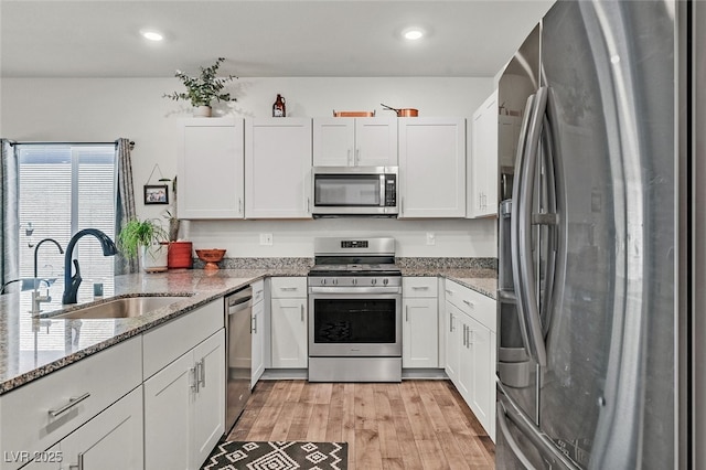 kitchen with white cabinetry, sink, light stone counters, and appliances with stainless steel finishes