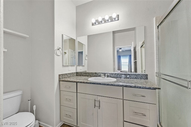 bathroom featuring vanity, a shower with door, and toilet