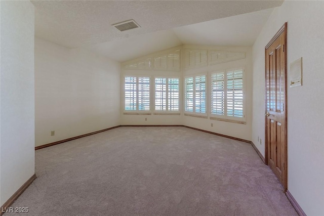 unfurnished room with vaulted ceiling, a wealth of natural light, visible vents, and baseboards