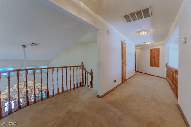 corridor with visible vents, light carpet, and baseboards