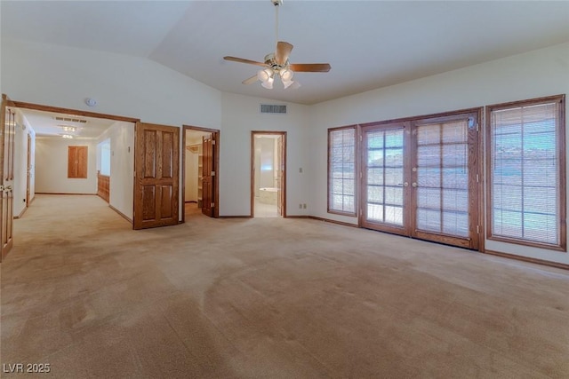 unfurnished room featuring plenty of natural light, visible vents, vaulted ceiling, and light colored carpet