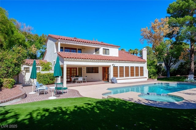 back of property featuring a chimney, stucco siding, a pool with connected hot tub, a patio area, and a tiled roof