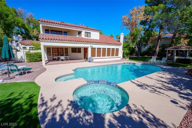 back of house with a patio, a tile roof, a gazebo, a pool with connected hot tub, and stucco siding